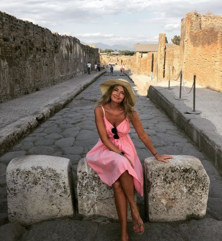 Paulina Porizkova in a pink dress wearing a hat poses for a picture at Pompel.